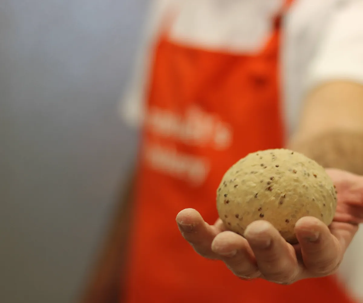 Raphaël holding a fresh roll in his orange apron